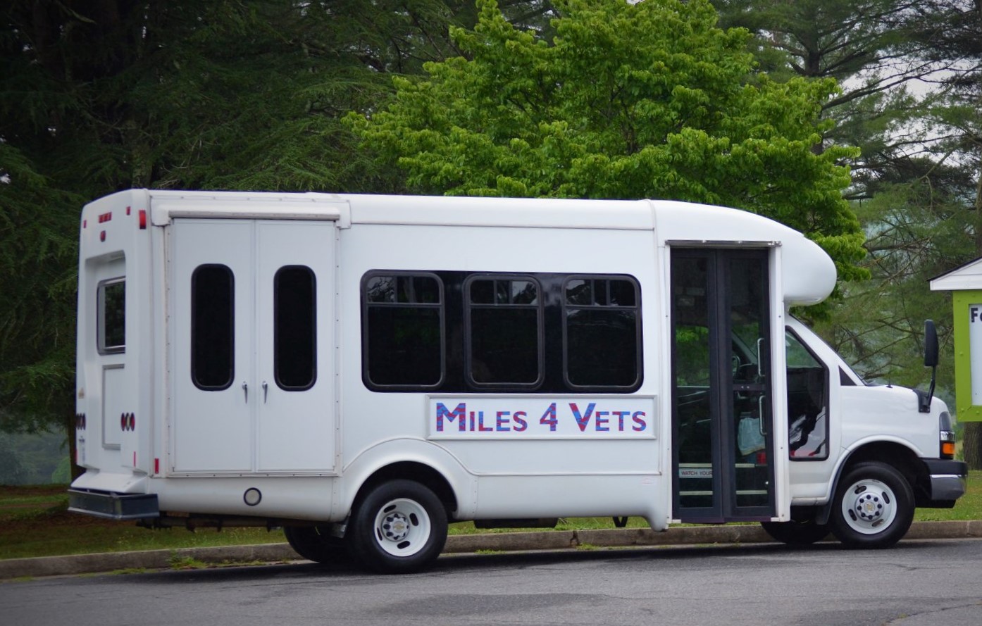 Southern Area Agency On Aging's "Miles 4 Vets" bus sits in a parking lot, with a tree overhead.